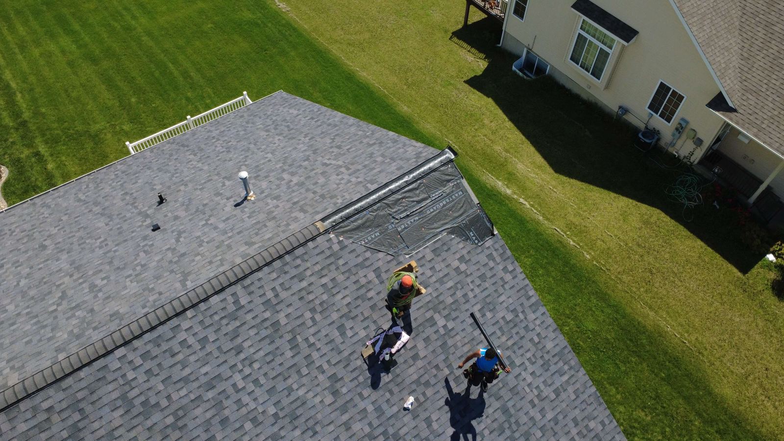 Roofing crew installing shingles, photographed from a drone