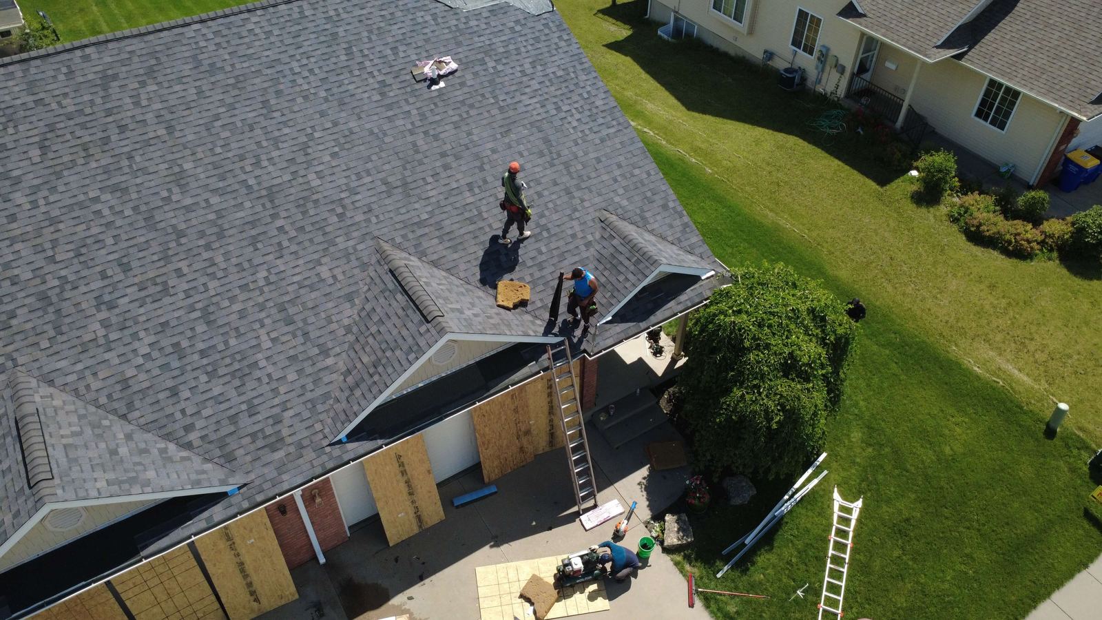 Roofers finishing ridge detail on a new shingle roof, drone photo