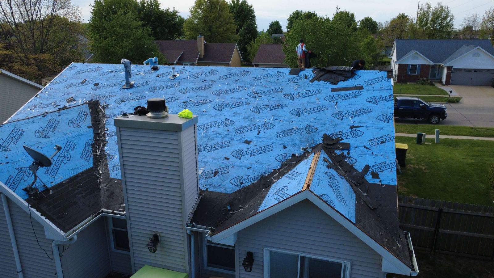 Roof tear-off in progress with underlayment exposed, aerial drone photo, Iowa City
