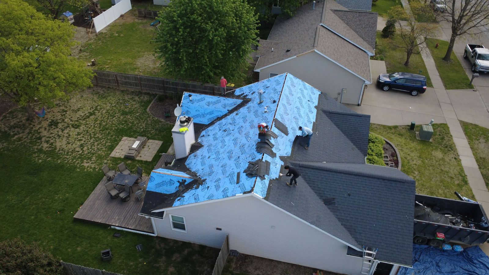 Job site during roof replacement with crew and materials staged, aerial photo